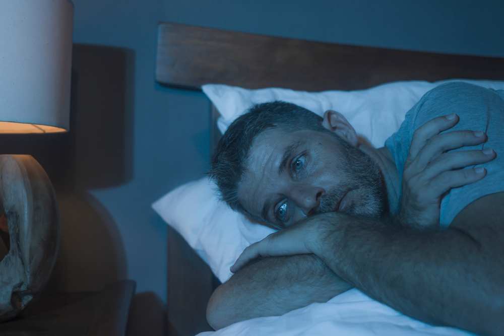 A man in awake in bed at night due to insomnia